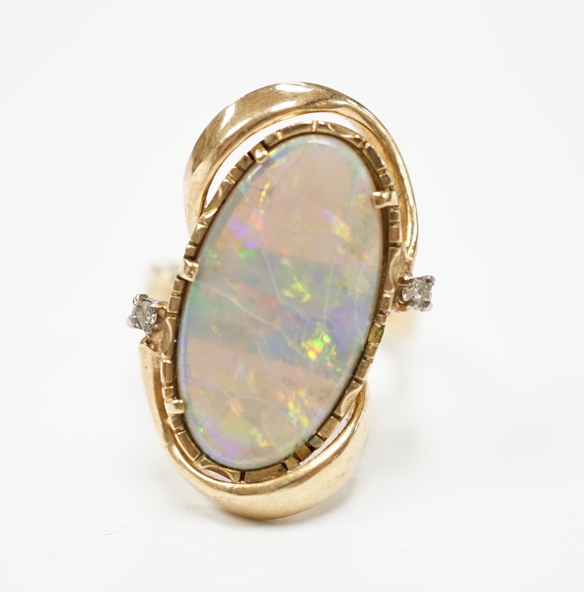 A yellow metal and oval cut black opal set dress ring, with two stone diamond chip set border, size M, gross weight 8.2 grams.